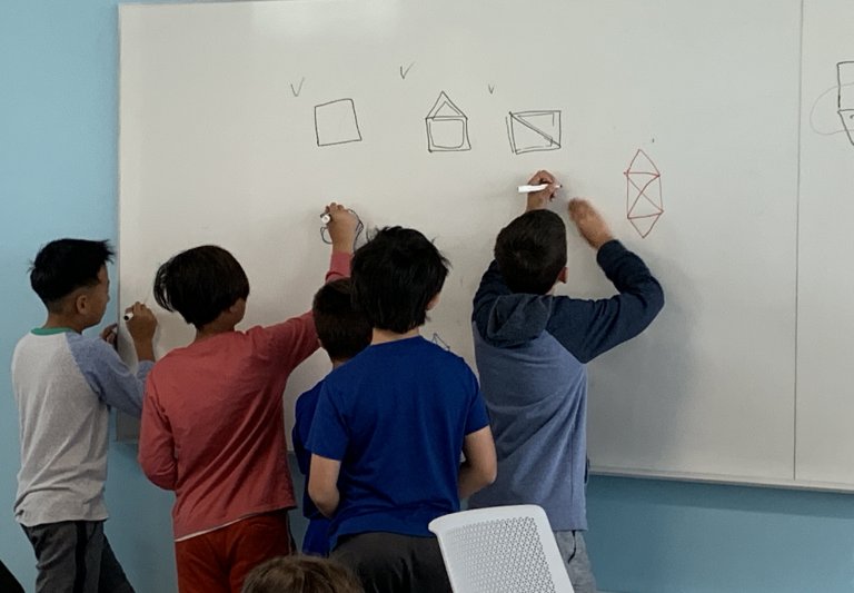 Saturday Academy students working on math problems on a white board