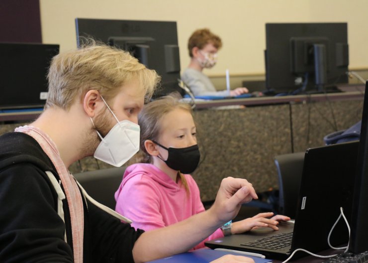 Instructor, Luke, works with a young student on a computer in Saturday Academy’s Animation Adventure summer camp