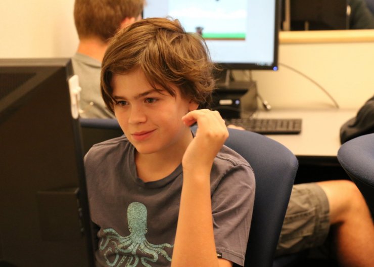 A student sits in front of a computer, working in Saturday Academy’s Electronic Music summer camp