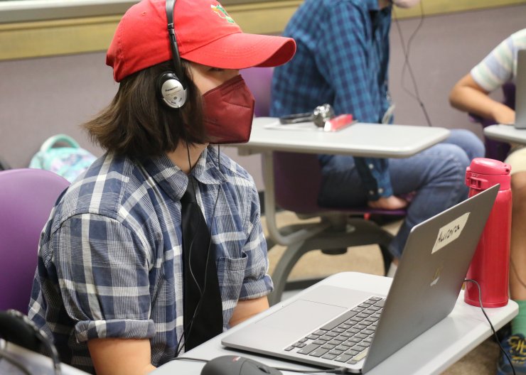 A student with headphones on in front of a laptop in Saturday Academy’s Electronic Music summer camp 