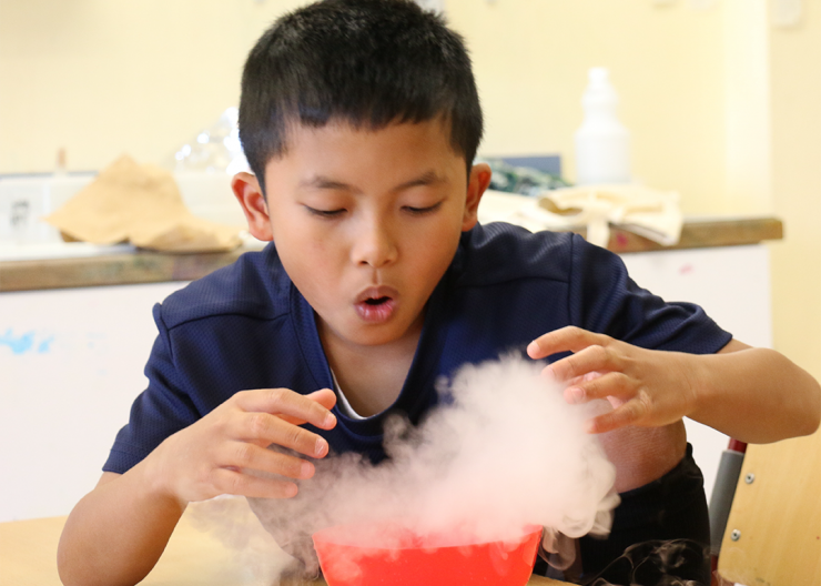 young kid watching in amazement smoke from a science experiment disperse