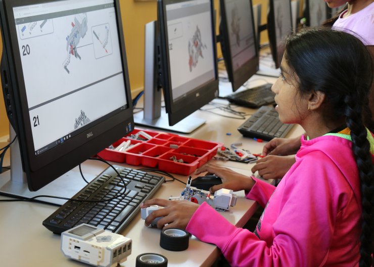 A Saturday Academy student builds with LEGOs and works on a computer in our LEGO WeDo summer camp. 