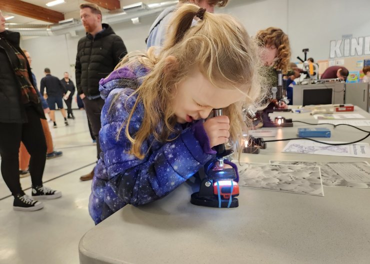 A young Saturday Academy camper is looking through a microscope