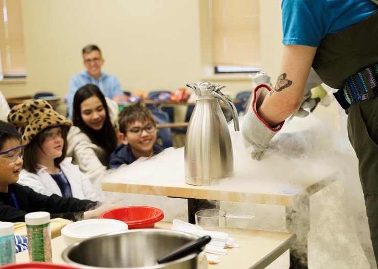 Student participating in an experiment to make ice cream using dry ice