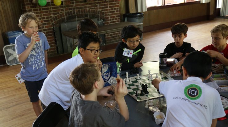 Group of Saturday Academy students playing chess during a summer camp
