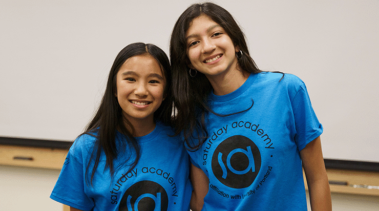 Two Saturday Academy students posing for a photo in their Saturday Academy t-shirts