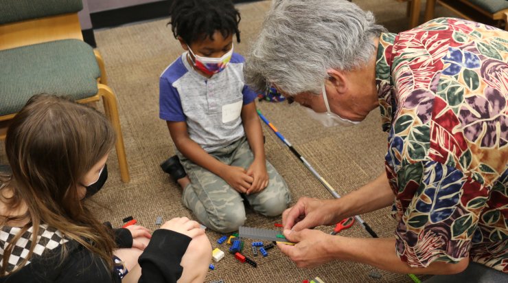 Two students working with Saturday Academy instructor Scott to build a tall tower using LEGOs and string