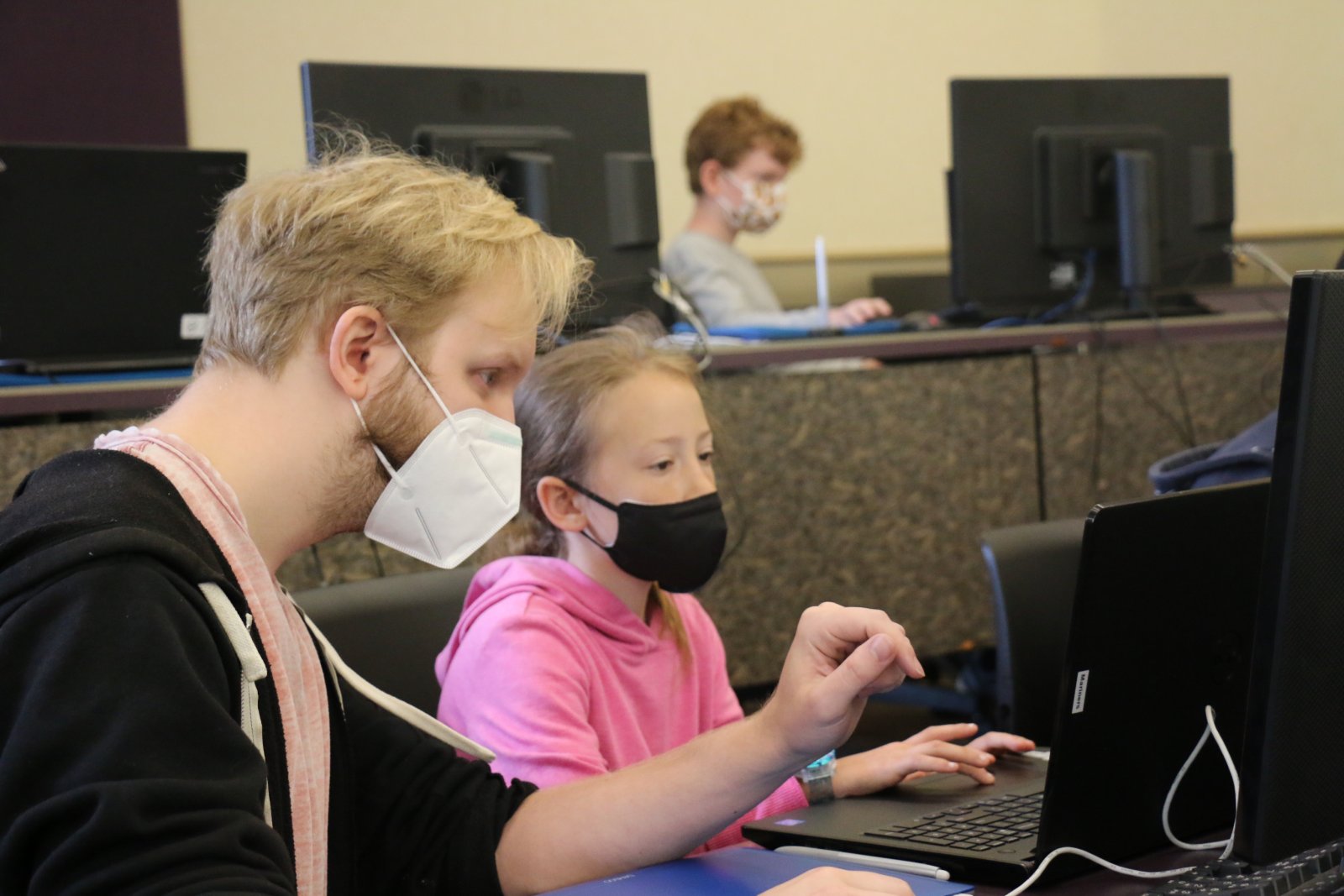 Instructor, Luke, works with a young student on a computer in Saturday Academy’s Animation Adventure summer camp