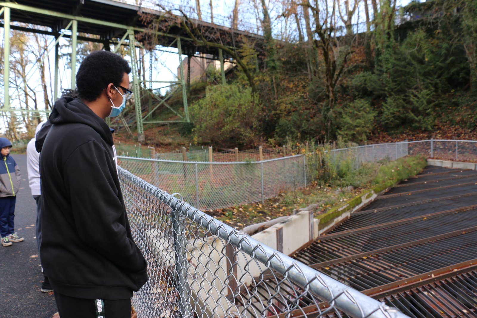 Student looking over the railing of a bridge in a nature park in a STEAM Career Tracks Saturday workshop