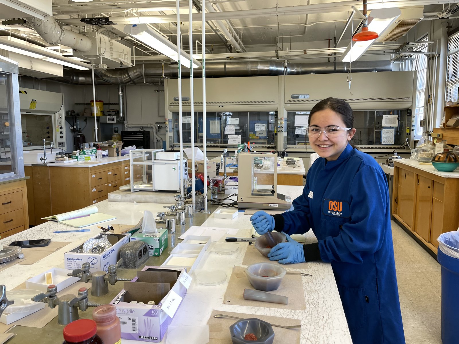 young adult scientist working in the lab, wearing a lab coat and safety glasses