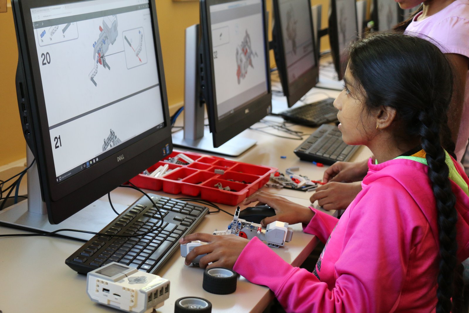 A Saturday Academy student builds with LEGOs and works on a computer in our LEGO WeDo summer camp. 