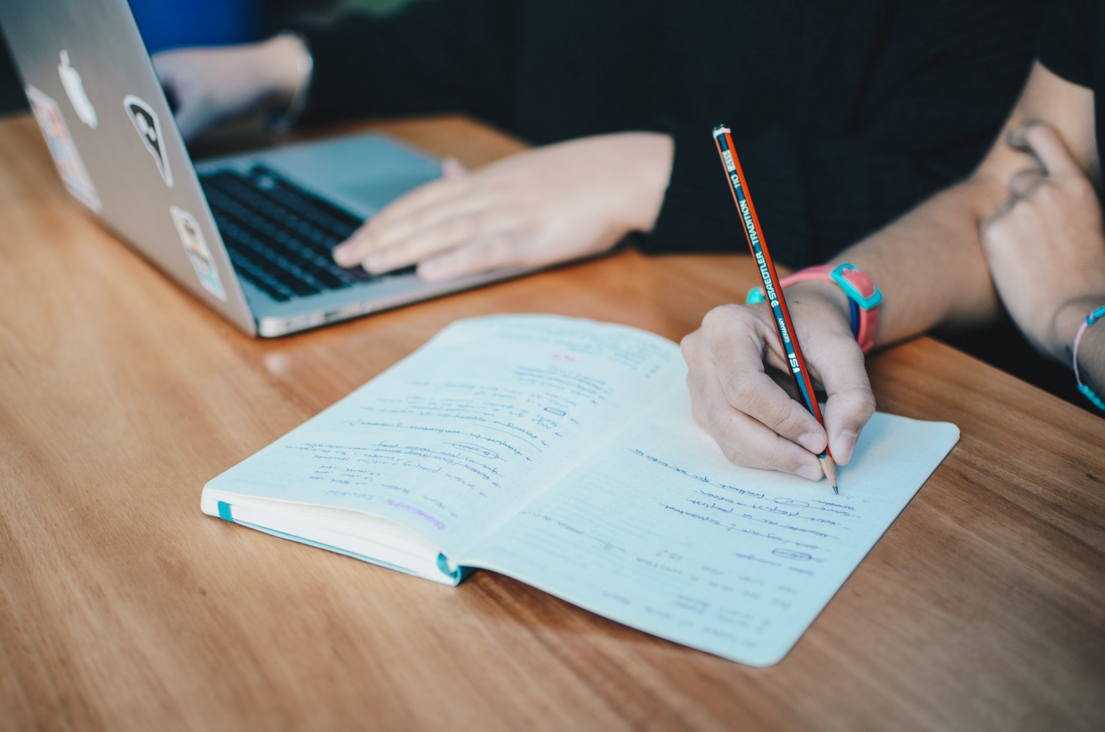 Students writing and working on a laptop